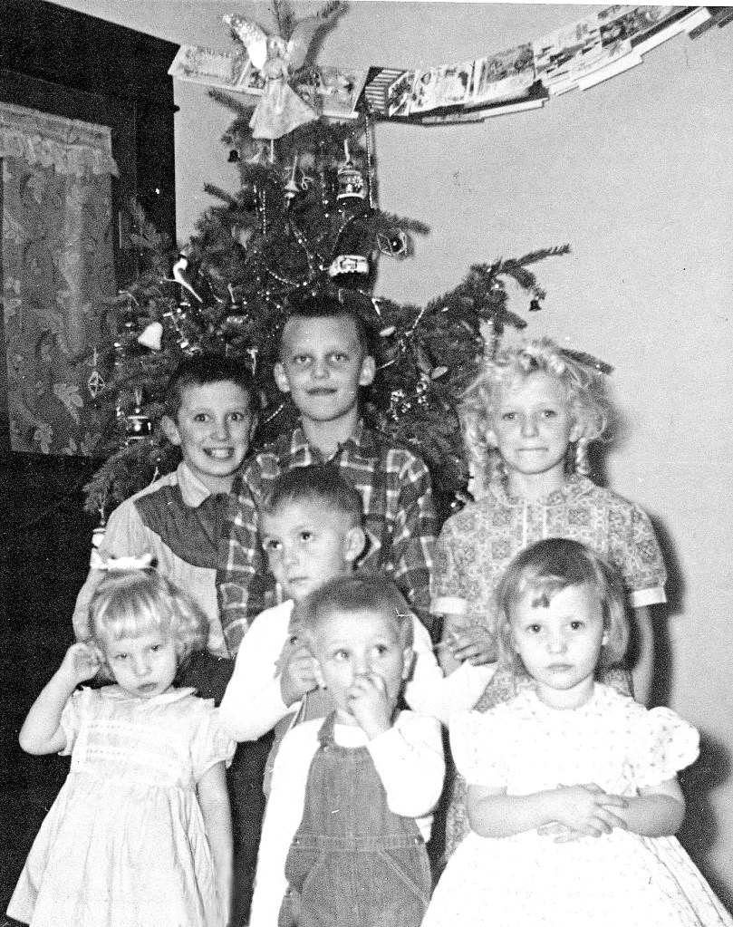 group of children in front of Christmas tree, circa 1960s.